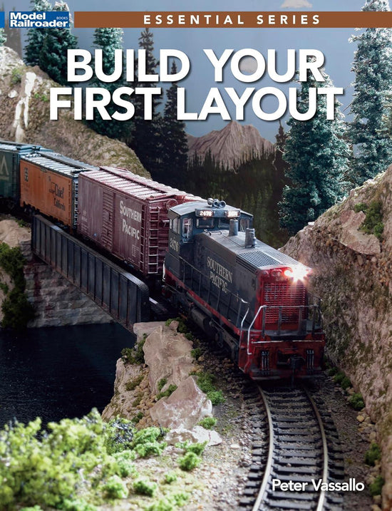Open book titled "Comprehensive Handbook for Constructing Your Initial Model Railroad Layout" with diagrams and instructions inside.